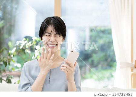 ソファーに座りスマートフォンを使う若い女性 ソファーに座りスマートフォンを使う若い女性 134722483