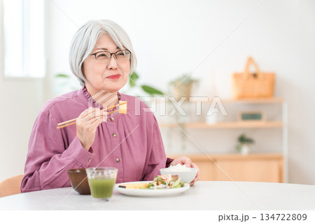 自宅のダイニングで食事をするグレイヘアーのシニア女性 134722809