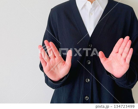 両手を前に出してストップのポーズをする女性 134723499
