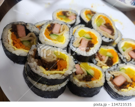 Delicious kimbap rolls filled with fresh vegetables, seasoned rice, and savory proteins, all wrapped in crisp seaweed. A perfect combination of flavor and texture in every bite. 134723535