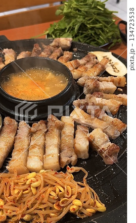 Grilled samgyeopsal, showcasing thick slices of pork belly sizzling on the grill. A popular Korean barbecue dish, capturing the essence of a delicious dining experience. 134723538