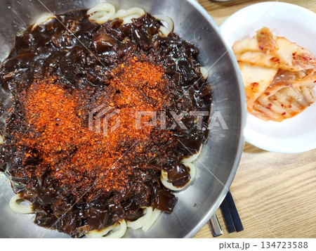 A bowl of jajangmyeon featuring chewy noodles coated in rich black bean sauce, topped with diced pork and vegetables. This iconic Korean-Chinese dish offers a savory and hearty flavor. 134723588