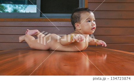 asian baby girl sitting in wooden table asian baby girl sitting in wooden table 134723874