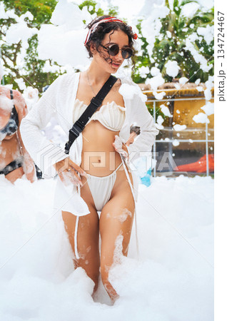 Happy slender sexy young woman in a swimsuit posing at foam party in summer on vacation 134724467