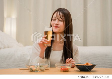 家の寝室で晩酌する若いアジア人女性（ビール,家飲み,飲酒習慣） 134725006