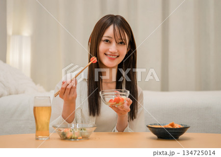 家の寝室でおつまみを食べながら晩酌する若いアジア人女性（ビール,家飲み,飲酒習慣） 134725014