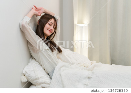 朝ベッドルームで熟睡,快眠できて笑顔でストレッチする女性 朝ベッドルームで熟睡,快眠できて笑顔でストレッチする女性 134726550
