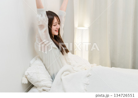 朝ベッドルームで熟睡,快眠できて笑顔でストレッチする女性 134726551