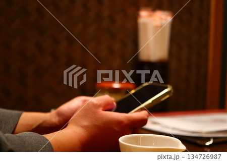 定食屋やラーメン店で一人外食する人の手元 スマートフォンを操作する様子 134726987