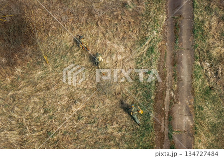 Men Dressed As US American Soldiers Of USA Infantry Of World War II sneaking around In spring Autumn Day. Soldiers prepare mortar for battle In dry grass. Aerial view elevated shot 134727484