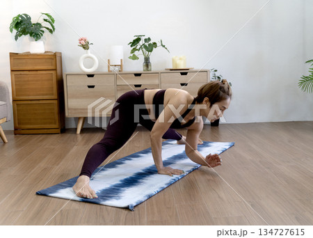 Asian woman in her 50s warms up on a yoga mat on the floor before starting Asian woman in her 50s warms up on a yoga mat on the floor before starting 134727615