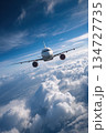 Commercial Airliner Soaring Above Clouds in Clear Blue Sky 134727735