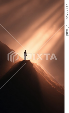 Inspirational Figure Standing in Sun Rays on Mountain Peak 134727737