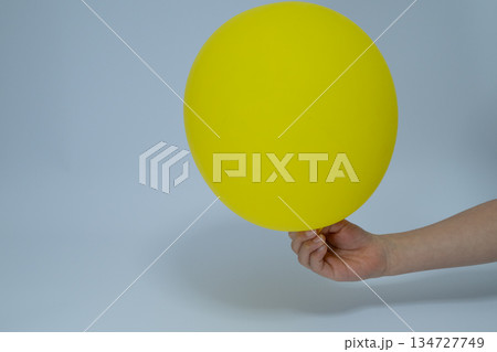 黄色の風船を持つ子供の手とコピースペース 134727749