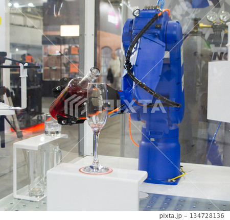 Robotic manipulators. Robot pouring liquid drink from bottle into glass. Industrial robot. Robot arm hand. Industrial manipulators for variety welding, material handling, palletizing. Robotization 134728136