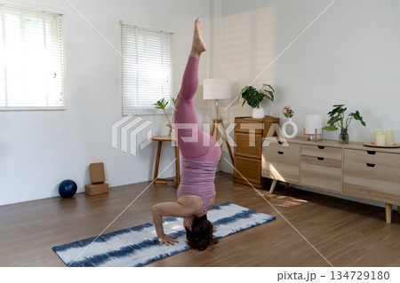 Elder woman exercising yoga in a head stand Sirsasana pose of placing Elder woman exercising yoga in a head stand Sirsasana pose of placing 134729180