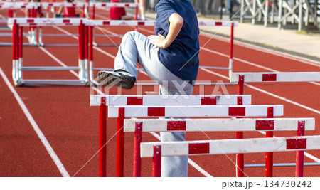 Young Athlete Practices Hurdles Drills on a Track Young Athlete Practices Hurdles Drills on a Track 134730242