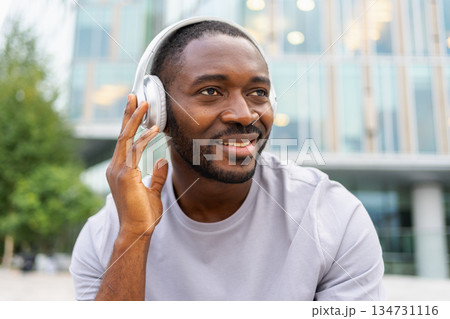 Music song concept. Good start day. Happy African American man listening modern hit on street in city. Person guy wearing headphones enjoy listening favorite music outdoor. People lifestyle joy 134731116