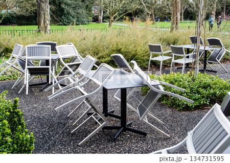 イスが斜めにテーブルにかけられた開店前のカフェのテラス ロンドン郊外のキューガーデンにて イスが斜めにテーブルにかけられた開店前のカフェのテラス ロンドン郊外のキューガーデンにて 134731595