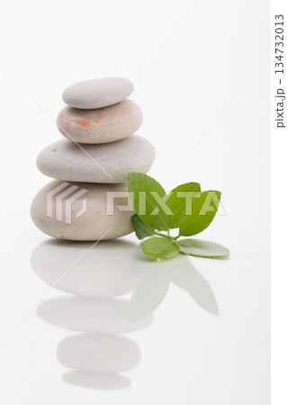 Balanced Stones with Green Leaves on White Background 134732013