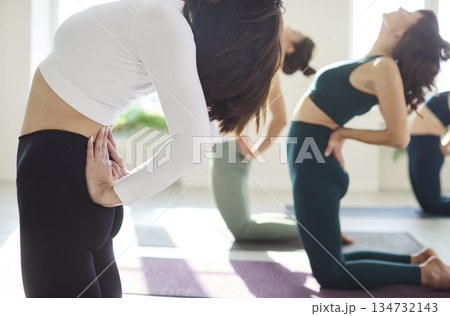 Close-up of women in yoga class doing camel asana, mindful backbend alignment 134732143