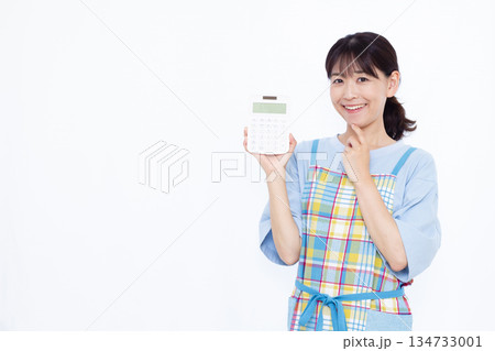 電卓を持って笑顔で考えている主婦 電卓を持って笑顔で考えている主婦 134733001