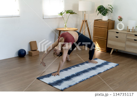 A fifty year old + woman doing yoga poses with her back stretched and her hands A fifty year old + woman doing yoga poses with her back stretched and her hands 134735117