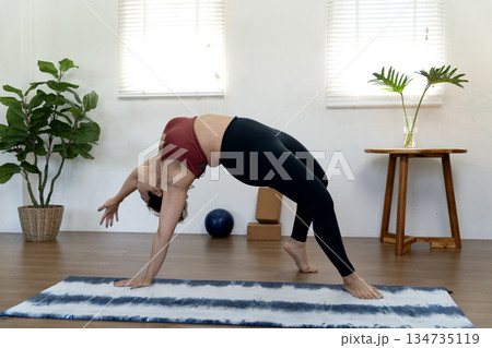 A fifty year old + woman doing yoga poses with her back stretched and her hands A fifty year old + woman doing yoga poses with her back stretched and her hands 134735119