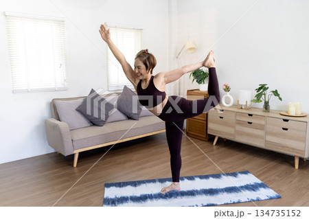 oman is doing yoga stand poses in her living room as a way to pass 50+ 134735152