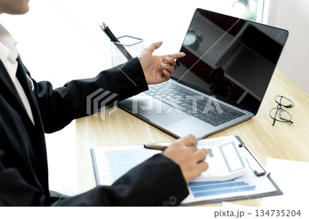 businesswoman Sitting at desk using smartphone and laptop with data from graph 134735204