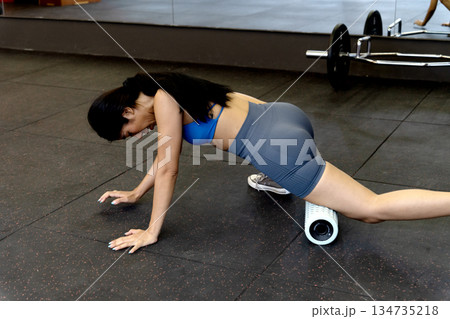 young woman is exercising while lying down using a circular device to roll on the floor young woman is exercising while lying down using a circular device to roll on the floor 134735218