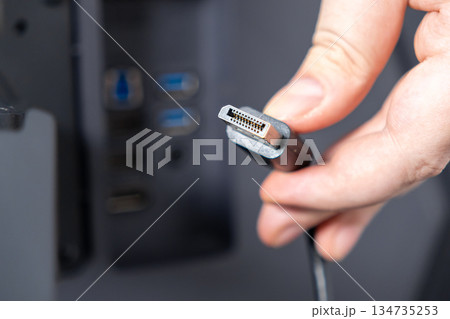 Hand holding DisplayPort cable connector, preparing connection to computer, symbolizing digital data transmission, display setup, and essential technology integration 134735253