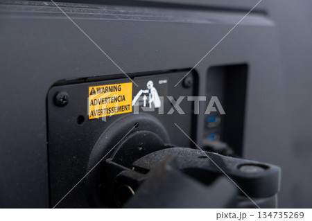 Electronic display back with yellow warning label WARNING ADVERTENCIA AVERTISSEMENT and safety graphic, guiding users on proper lifting and careful equipment handling 134735269