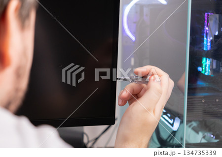 Technician's hand using a precise voltage tester tool on a computer monitor, symbolizing detailed electronics diagnostics, complex hardware troubleshooting, and expert repair 134735339