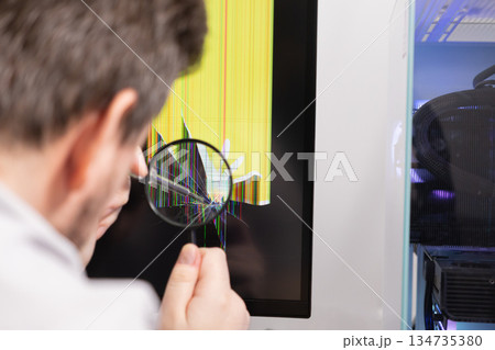 Expert technician uses a magnifying glass to inspect a cracked computer monitor screen, depicting electronic device repair, damage assessment, and IT support Expert technician uses a magnifying glass to inspect a cracked computer monitor screen, depicting electronic device repair, damage assessment, and IT support 134735380