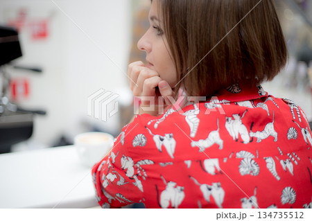The young girl looks away in the background of a shopping cafe. Back view 134735512