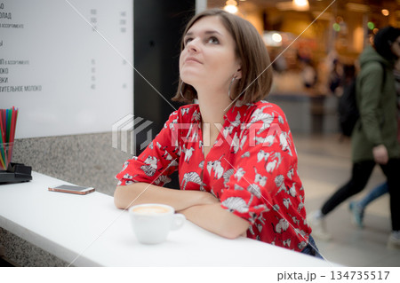 Beautiful girl with short hair sitting pensively at a cafe 134735517