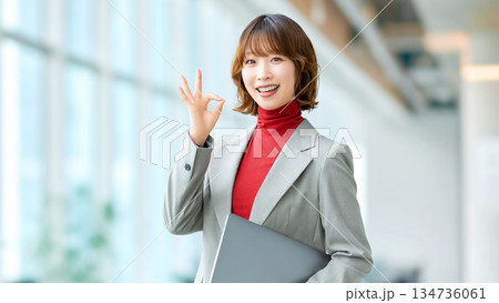 パソコンを持ってOKポーズをする女性・ビジネスウーマン 134736061