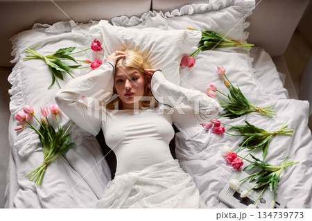 Calm individual amidst blossoms, Individual lying peacefully in bed filled with blooming flowers 134739773