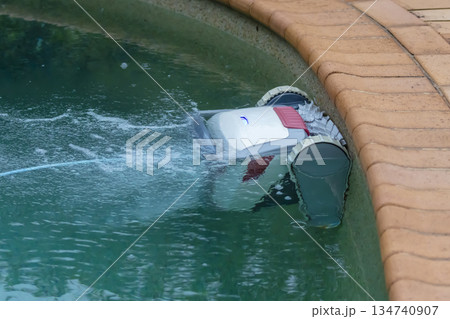 A swimming pool cleaning robot in action in a domestic pool 134740907