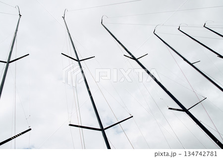 Few masts of sailboats moored in yacht club, ropes and aluminum, cloudy weather 134742781