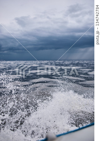 splashing water from under the rubber boat in stormy weather, sailing regatta in the Gulf of Finland in heavily rain splashing water from under the rubber boat in stormy weather, sailing regatta in the Gulf of Finland in heavily rain 134742784