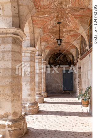 A long hallway with pillars and a plant in a vase A long hallway with pillars and a plant in a vase 134742895