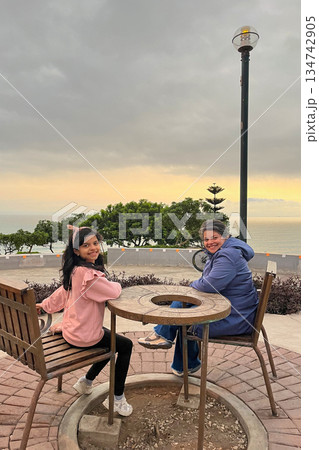 Mother and daughter is sitting at a table in a park Mother and daughter is sitting at a table in a park 134742905