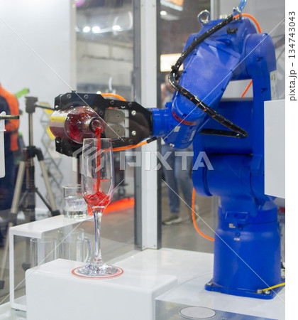Robotic manipulators. Robot pouring liquid drink from bottle into glass. Industrial robot. Robot arm hand. Industrial manipulators for variety welding, material handling, palletizing. Robotization 134743043