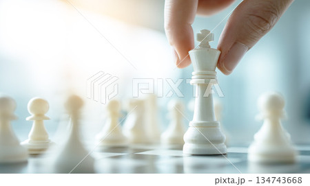 戦略ゲームでチェスの王様の駒を動かすビジネスマンの手 134743668