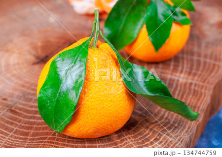 Fresh oranges with green leaves sit on wooden surface Fresh oranges with green leaves sit on wooden surface 134744759