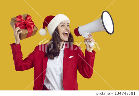 Happy woman in Christmas hat advertising holiday sale and yelling through megaphone Happy woman in Christmas hat advertising holiday sale and yelling through megaphone 134745581