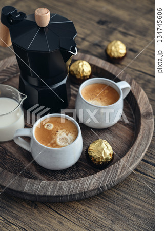 Black moka pot coffee maker with wooden handle and two cups of coffee Black moka pot coffee maker with wooden handle and two cups of coffee 134745606