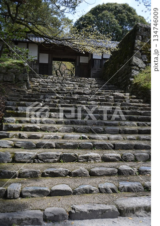 日本の神社へと続く趣のある古い石段と木造の門 134746009